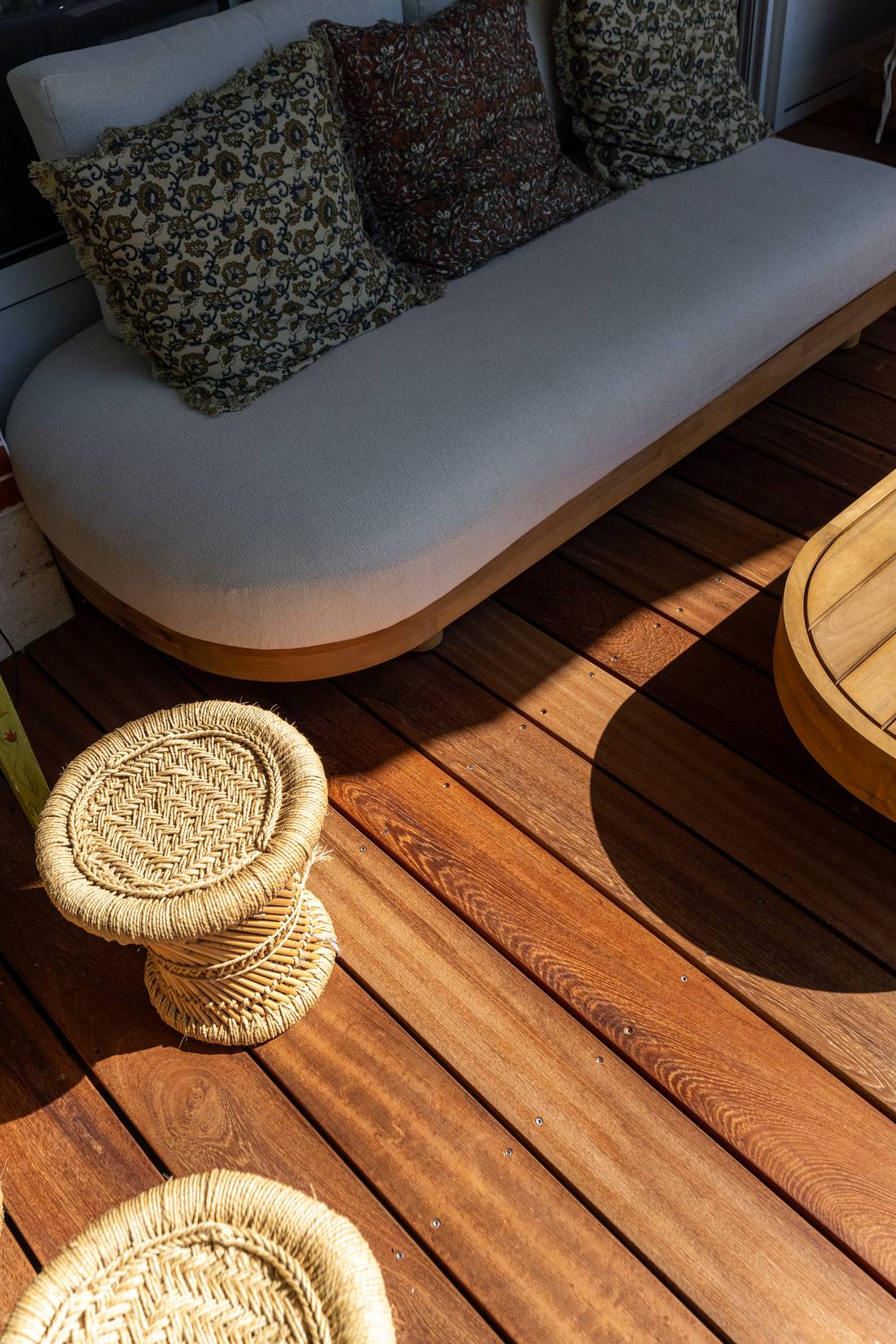 Détail d'une banquette d'extérieur et de poufs en fibre naturelle sur une terrasse en bois à Arcachon